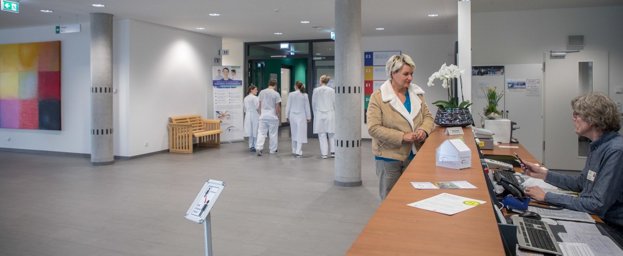 Angehörige im Gespräch mit Empfangsmitarbeiter der Klinik. 