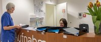 Pflegefachfrau am Tresen der Aufnahmestation im Gespräch mit Kollegin.